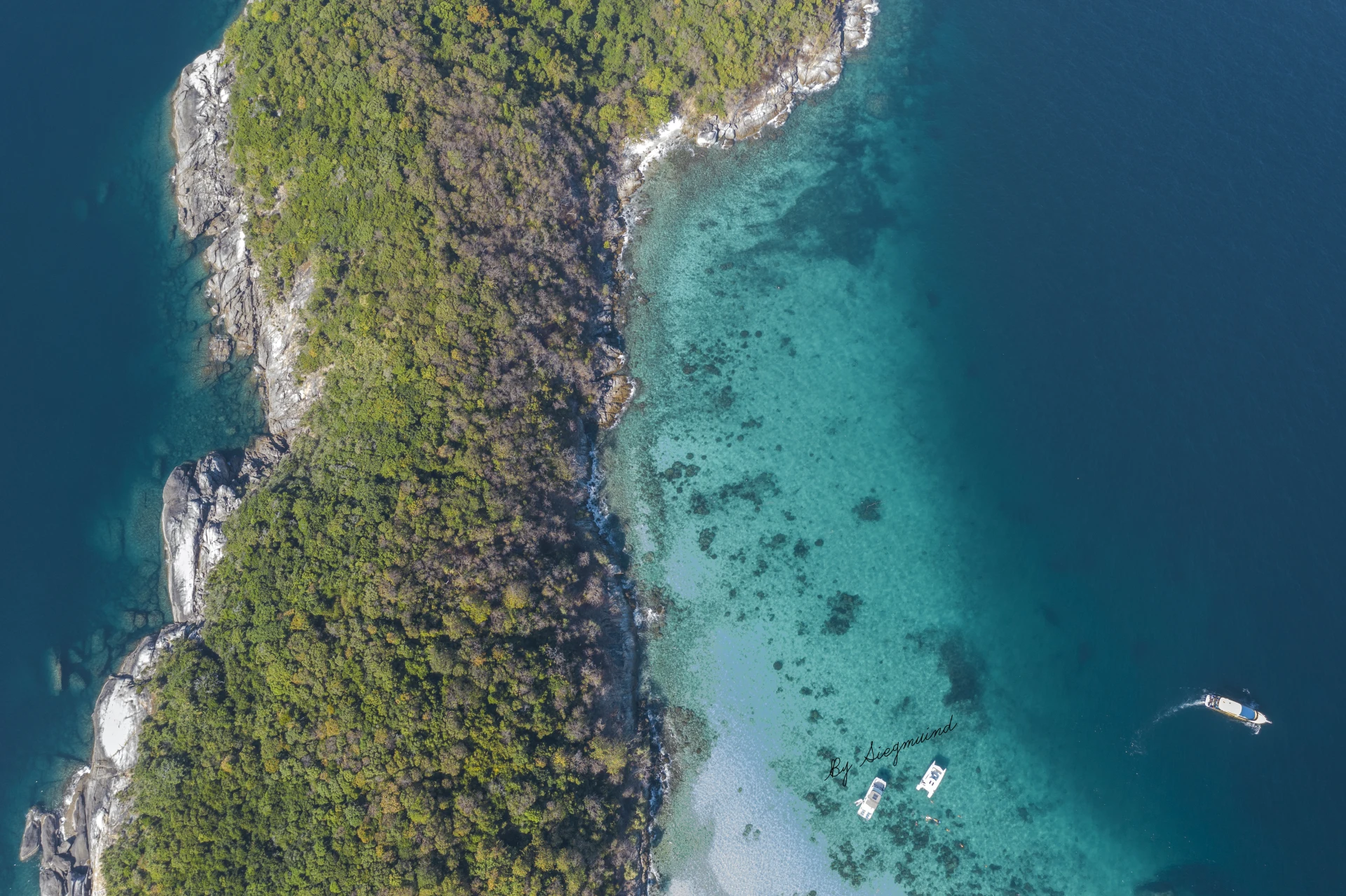 Top view of the tropical island of Phuket with lush greenery, turquoise water, and boats near the shore