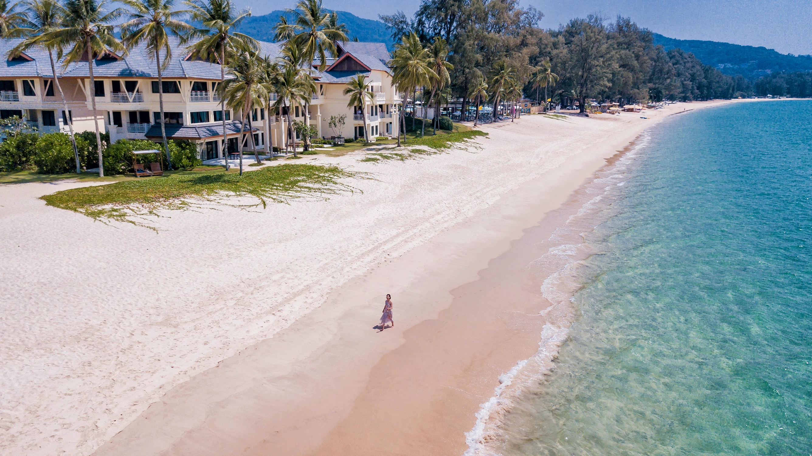 Modern residential buildings of the Laguna hotel with balconies, surrounded by tall coconut palms on the shore
