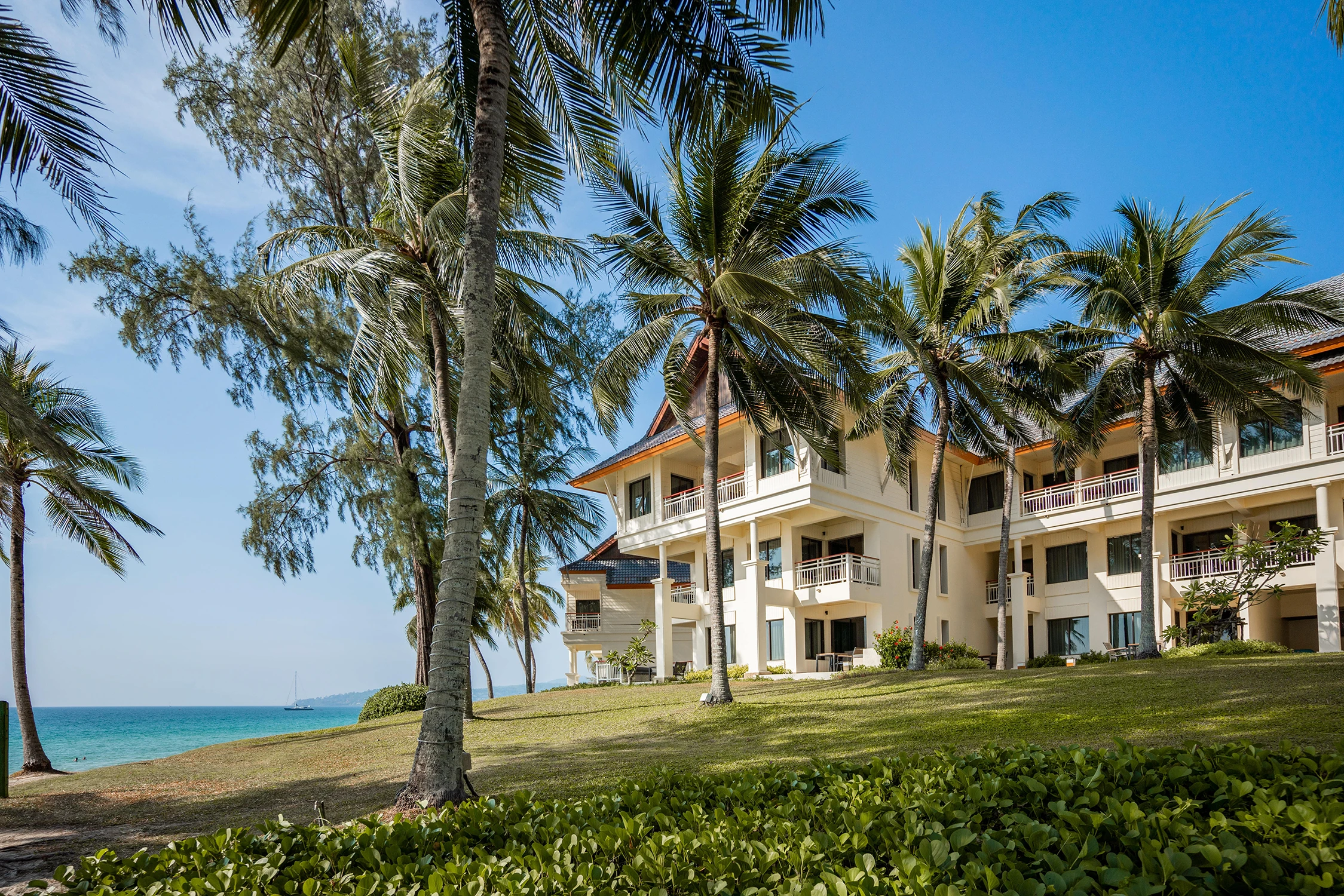 Three-story snow-white buildings of the Laguna hotel surrounded by tall palm trees on the seashore